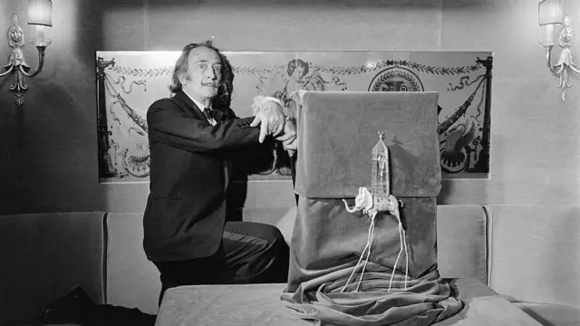 Сальвадор Дали рядом со своей скульптурой "Слоножираф"