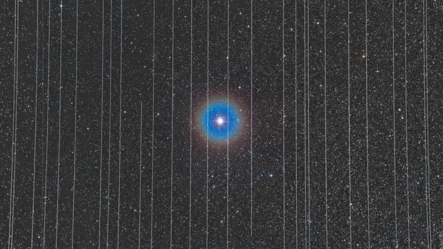 Los rastros de luz de satélites en movimiento componen esta fotografía de una estrella.