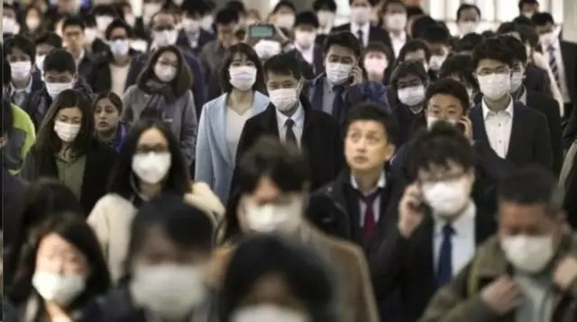 Pessoas andamroleta para nomesmáscara na rua no Japão