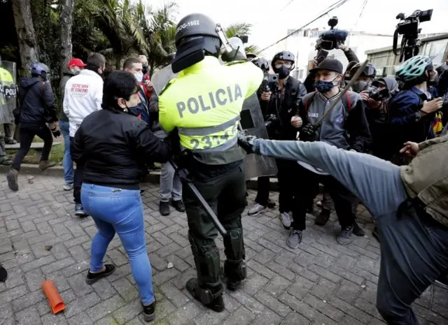 Manifestante chutando policial