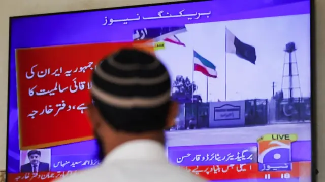 A man looks at a television screen after the Pakistani foreign ministry said the country conducted strikes inside Iran targeting separatist militants