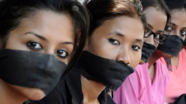 Miembros de una asociación de fotoperiodistas con bandas negras en la boca, protestan por la violación de una colega.