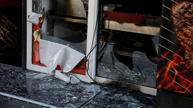 Polomljeno staklo i srča na podu ispred zapaljenog kafića