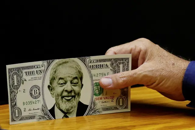 Mão segura dólar falso com rosto do Lula