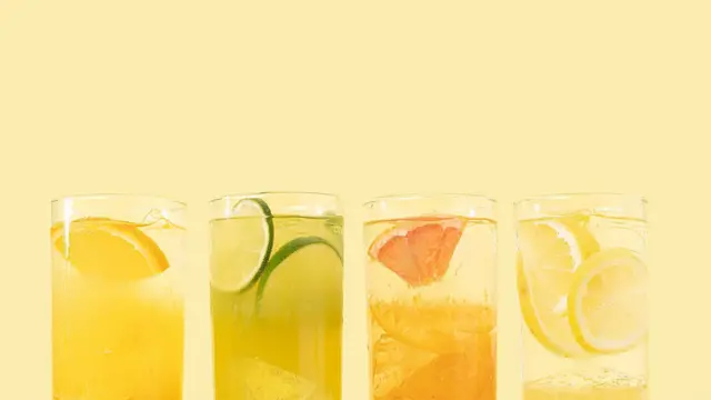 Portakal suyunun farklı türleri, portakal misket limonu greyfurt ve limon dilimleriyle dört bardak sıralanmış. 