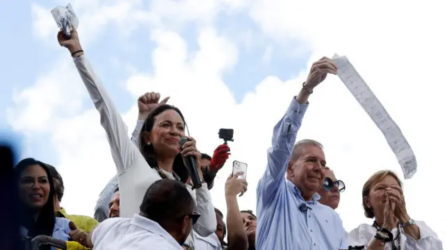 María Corina Machado e Edmundo Gonzalez erguem os braços, rodeados por outras pessoas,renda extra apostascimarenda extra apostascarrorenda extra apostassom