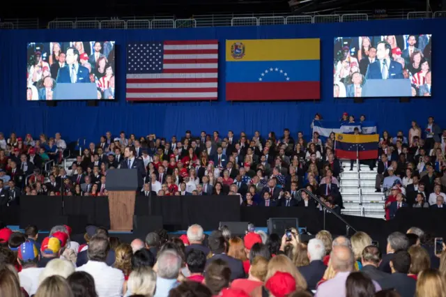 Rubio discursando, observado por dezenashistorico aviator betnacionalpessoashistorico aviator betnacionalauditório com bandeiras dos EUA e da Venezuela 