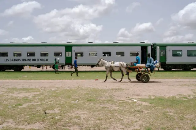 Une calèche passe devant le train à Bambey, en route vers Touba, au Sénégal,