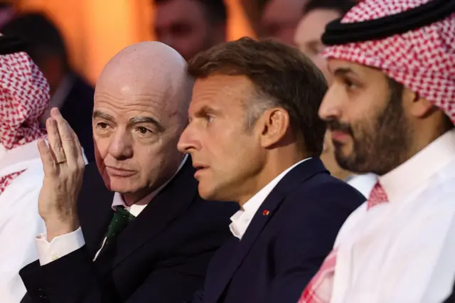 ولي العهد السعودي (يمين) وبجوار الرئيس الفرنسي مانويل ماكرون ورئيس الفيفا جياني إنفانتينو