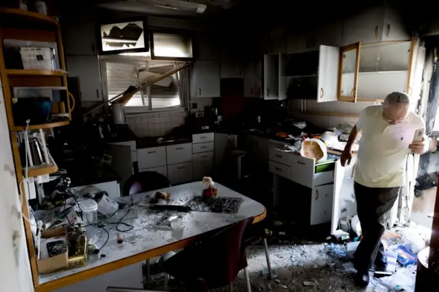 صورة لرجل يفحص أضرار لحقت بمطبخ منزله المدمر. 