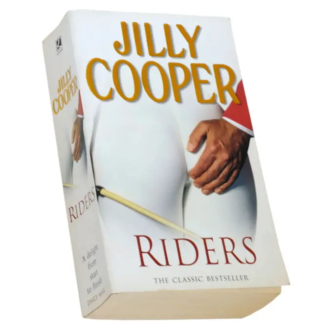 Обкладинка книги Джиллі Купер "Вершники", рука тримає білі сідниці