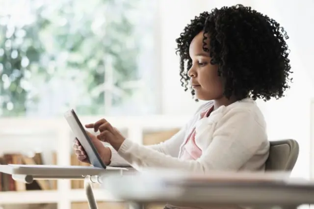 Niña escribiendo en una tableta