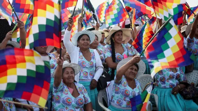 Mujeres levantas banderas indígenas en una reunión política.