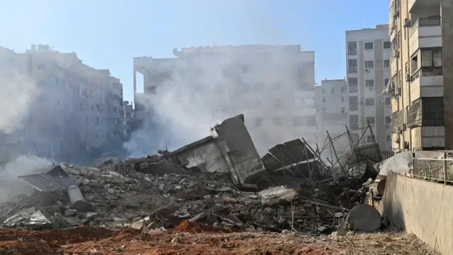 صورة تظهر ركاماً لمبنى مدمر في حارة حريك بالضاحية الجنوبية لبيروت مع تصاعد لأعمدة الدخان في أعقاب غارة إسرائيلية 