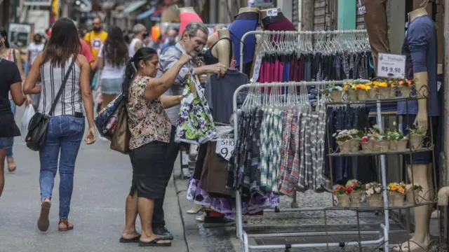 Mulher comprando roupas em loja de rua no Rio de Janeiro