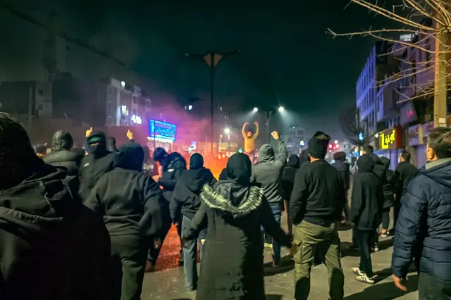 شامگاه ۹ ژانویه معترضان در محله تهرانپارس تهران شبانه در اطراف آتشی در جریان اعتراضات سراسری ایستاده‌اند و شعار می‌دهند.