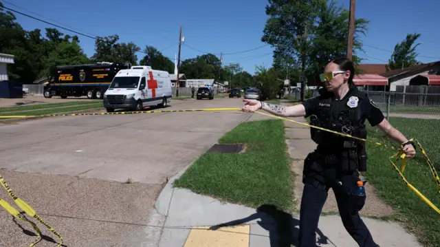 Policajka sa naočarima za sunce drži traku za uviđaj na terenu