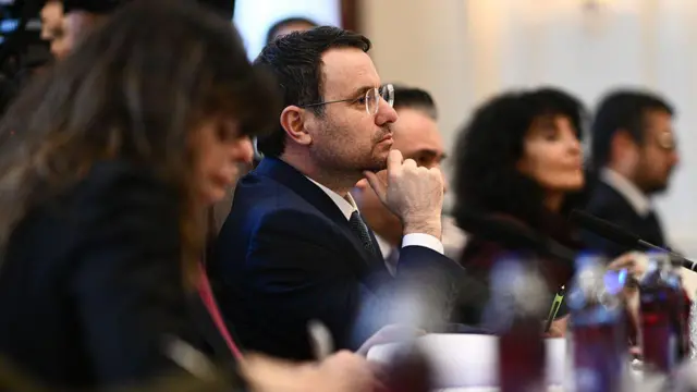 Odakta gürlek var dikey uzanan bir masada sağında ve solunda odak dışında resmi giyimli kadınlar.