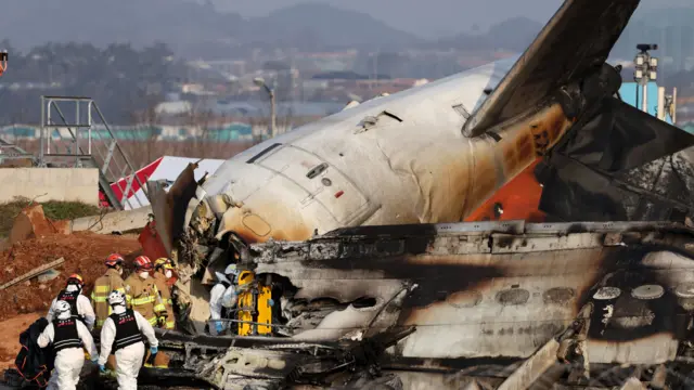 Bombeiros, algunsqual melhor mercado de apostas esportivastrajes marrons e outrosqual melhor mercado de apostas esportivasbranco e preto, vasculham os destroços da aeronave Jeju Air. De costas para a câmera. Os destroços são quase identificáveis ​​como um avião, exceto pela cauda