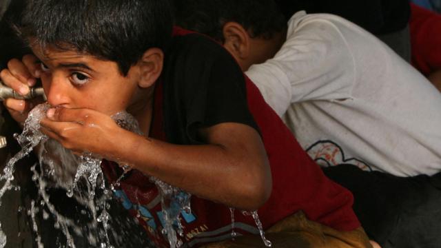 Crianças bebendo água diretamente na torneira