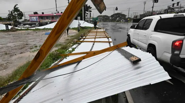 Powalony płot w St. Catherine na Jamajce, z prawdej strony widoczny biały samochód