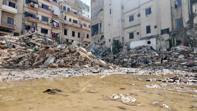 بقايا أنقاض مبنى منهار، حيث تتناثر كتل الخرسانة والحديد بين الغبار في مشهدٍ يعكس حجم الدمار الذي خلّفه الانهيار.