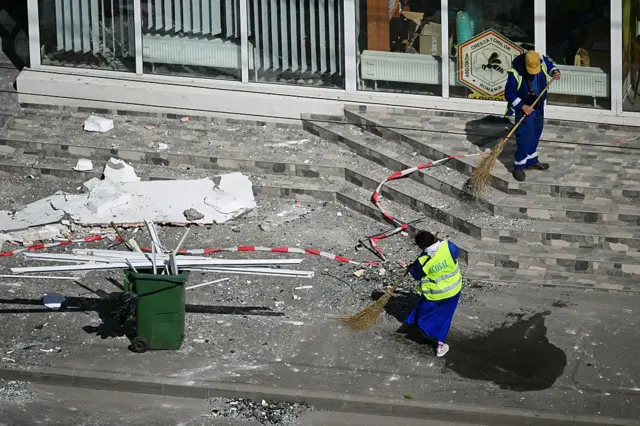 Муніципальні працівники розчищають завали з вулиці після того, як російський безпілотник врізався в багатоквартирний будинок у Галаці, на сході Румунії.