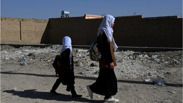 Afghan schoolgirls walk along a path as they return from school in Mazar-i-Sharif on 30 October, 2021. 