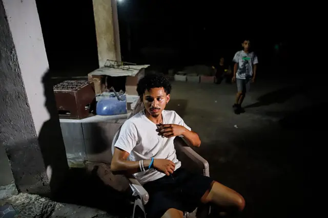 Emerson Colindres vestido con pantalón corto y camiseta blanca, sentado en una silla plástica en su casa de El Ojochal, Marcovia, Honduras, el 24 de junio de 2025. (Foto: JORGE CABRERA/AFP via Getty Images)