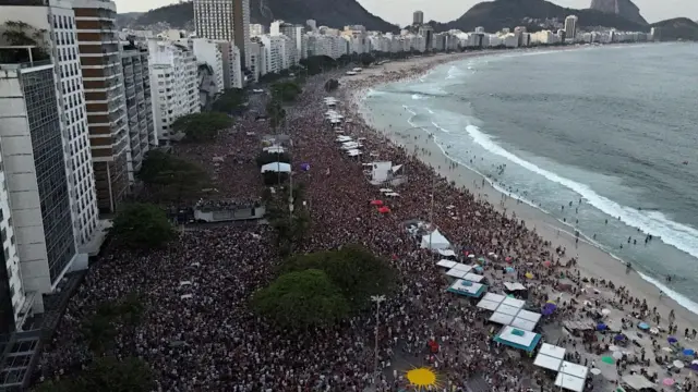 Foto aérea da orla de Copacabana lotada de pessoas. 