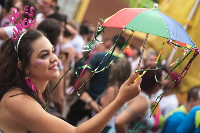 Mulher segurando sombrinha decorada com fitinhas metalizadas