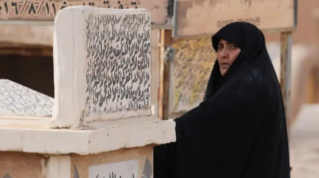 امرأة تزور قبور أقاربها في أول أيام عيد الفطر في مدينة النجف في العراق