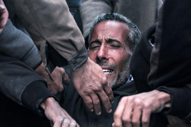 یک مرد فلسطینی  در کنار سردخانه شهدای الاقصی برای یکی از بستگان خود که در جریان بمباران شبانه اسرائیل در دیربلاح در مرکز نوار غزه  کشته شده سوگواری می‌کند