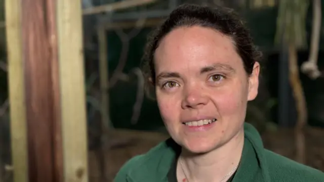 Maxine Bradley tiene ojos marrones y el pelo recogido, y sonríe a la cámara en un zoológico. Lleva un abrigo verde y esponjoso.