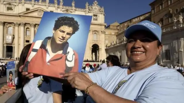 Seorang umat Katolik memegang poster Carlo Acutis yang telah diangkat sebagai santo di Vatikan, pada Minggu (07/09).