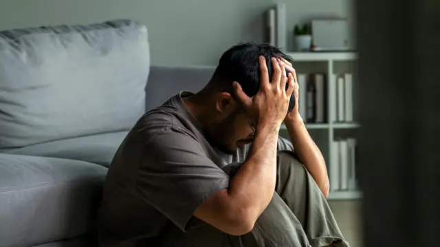 Yere kapanıp yüzünü elleriyle kapatmış genç bir erkek