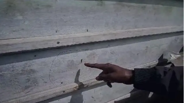 Kerabat keluarga korban menunjukkan lubang di dinding kayu rumah yang terkena peluru. 