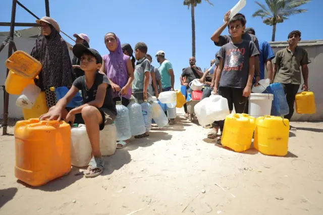 Un grupo de personas con garrafas hace cola para conseguir agua.