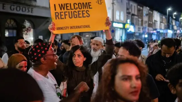 Une femme portant une banderole sur laquelle on peut lire : « I welcome refugees » (J'accueille les réfugiés) lors d'une contre-manifestation après une série d'émeutes anti-immigration qui ont secoué le Royaume-Uni en août 2024.