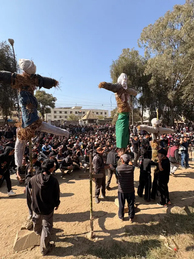 भीड़ के साथ बीच में खड़े पुतले