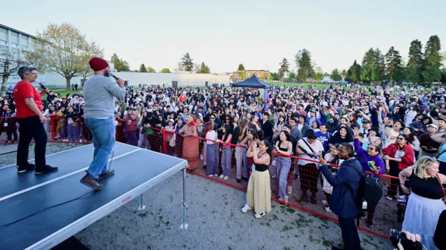 Два человека на сцене перед собравшимися людьми.
