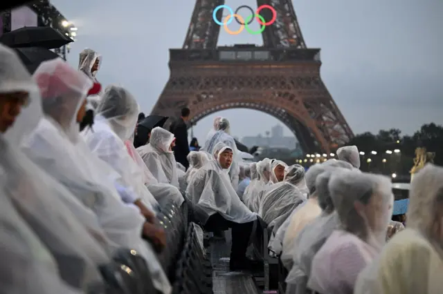 Abarorerezi bari bicaye imbere y'umunara wa Eiffel imvura ari je je je. 