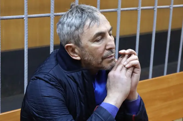 Фото Умара Джабраилова от 2017 года. Снимок сделан во время заседания суда, за спиной у Джабраилова — решетка.