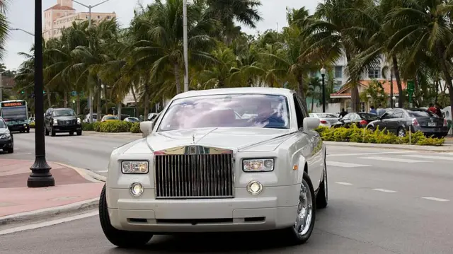 A luxury silver Rolls Royce turning on a road