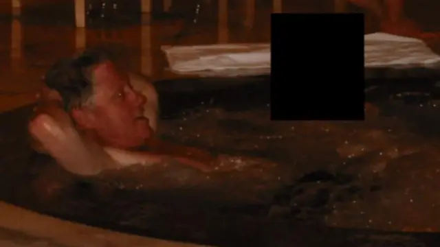 Clinton odpoczywa w czymś, co przypomina jacuzzi, z rękami założonymi za głową.