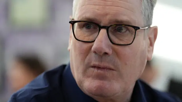 黒縁めがねをかけたスターマー英首相が口を閉じ、左の方を見ている