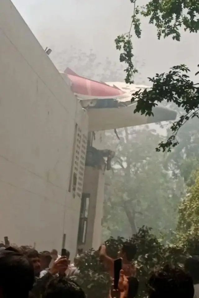 বিমানের লেজের অংশ ঝুলছে ওই ভবন থেকে 