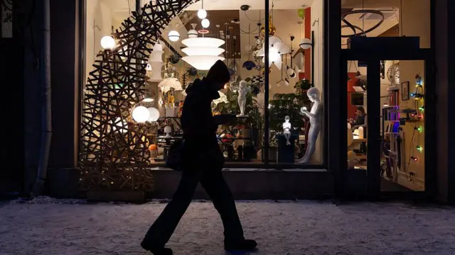 Чоловів ввечері йде повз світлий магазин