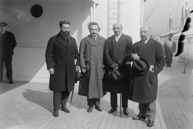 Quatro homens lado a lado, aparentemente em um navio, posando para foto