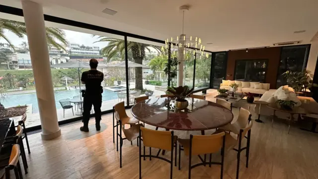 Agente da polícia federal está de costas em sala de jantar de casa de luxo alvo da operação contra lavagem de dinheiro em postos de combustíveis